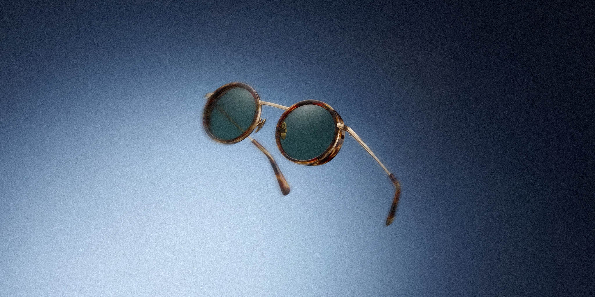 Round tortoiseshell sunglasses with green lenses on a blue gradient background