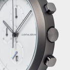 Close-up of a modern chronograph watch with white dial, subdials, and brushed metal case
