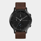 Black chronograph watch with brown leather strap and date display on white background