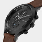 Modern black chronograph watch with brown leather strap and minimalist dial