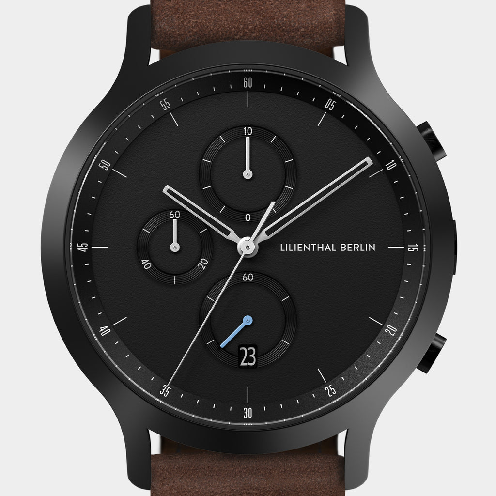 Black chronograph watch with subdials, date display, and brown leather strap