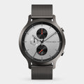 Minimalist silver chronograph watch with black mesh strap, three subdials, and red accents.