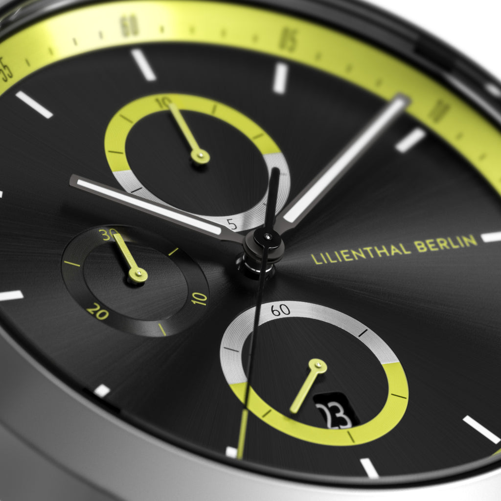 Close-up of a modern black chronograph watch dial with yellow accents and subdials