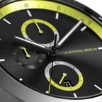 Close-up of a modern black chronograph watch dial with yellow accents and subdials