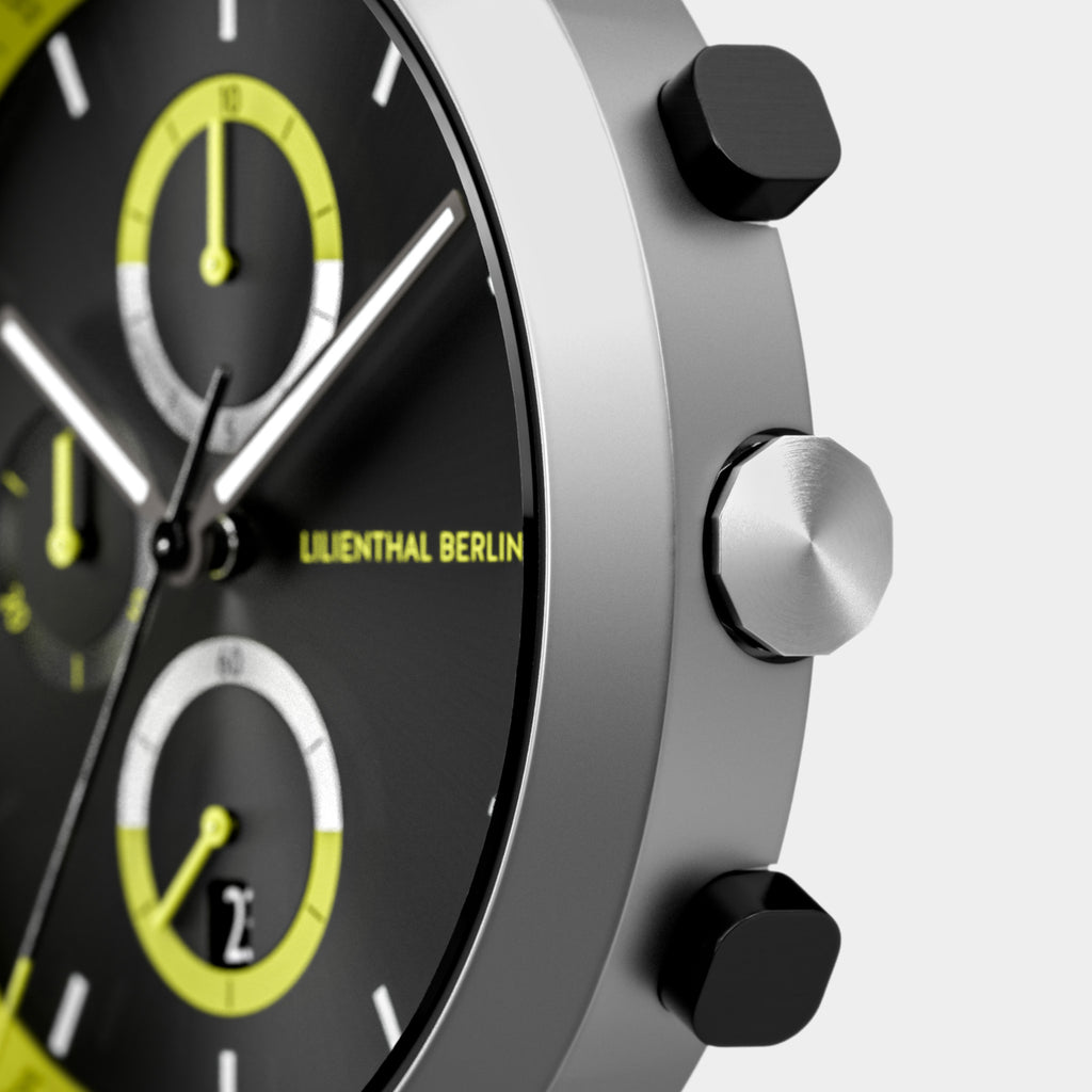 Close-up of a modern chronograph watch with yellow accents and stainless steel case.