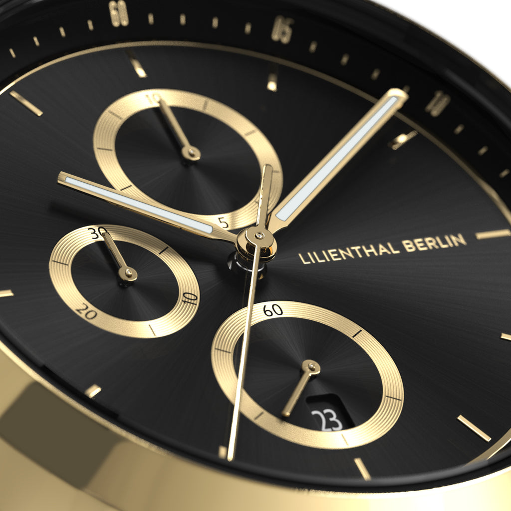 Close-up of a black and gold chronograph watch face with subdials and date display