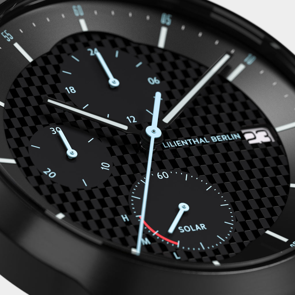 Close-up of black chronograph watch face with carbon fiber texture, subdials, and solar indicator