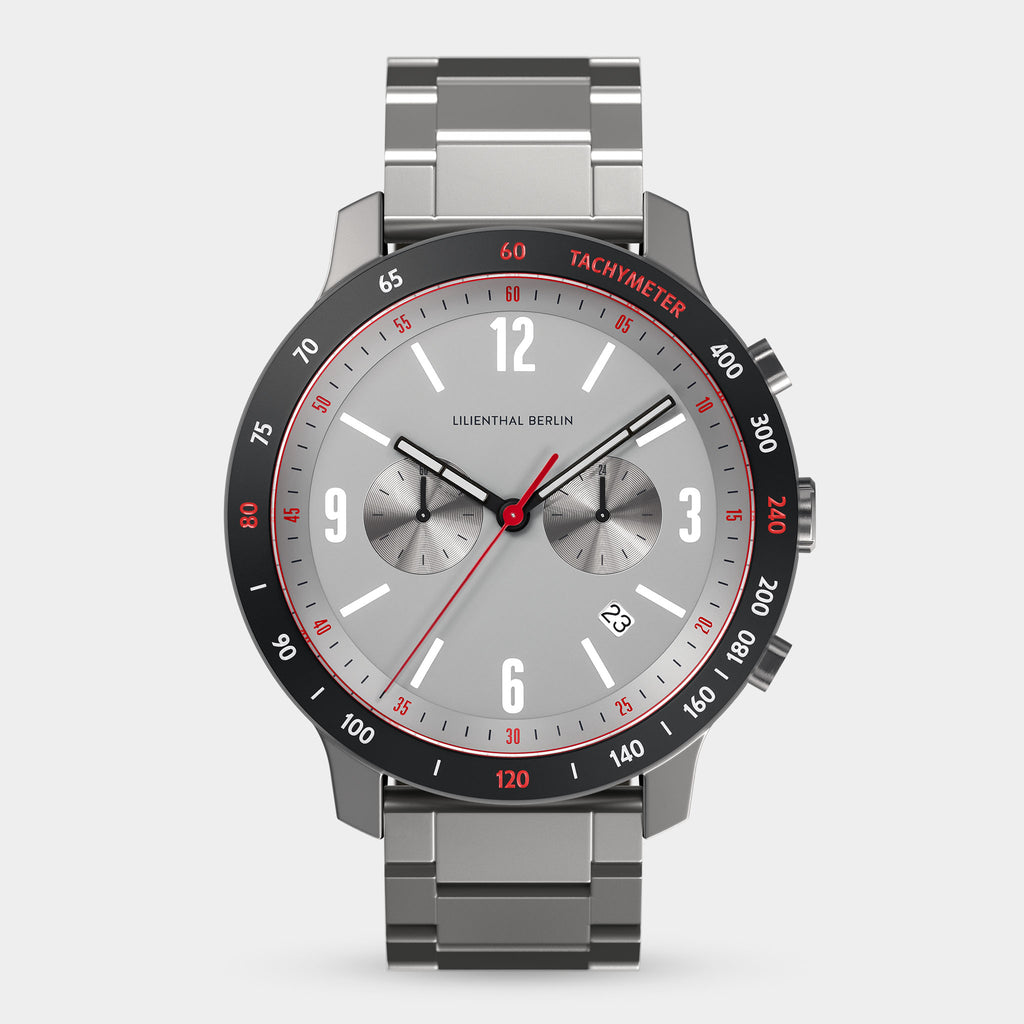 Stainless steel chronograph watch with grey dial, red tachymeter bezel, and date display.