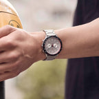 Stainless steel chronograph watch with silver dial worn on wrist outdoors