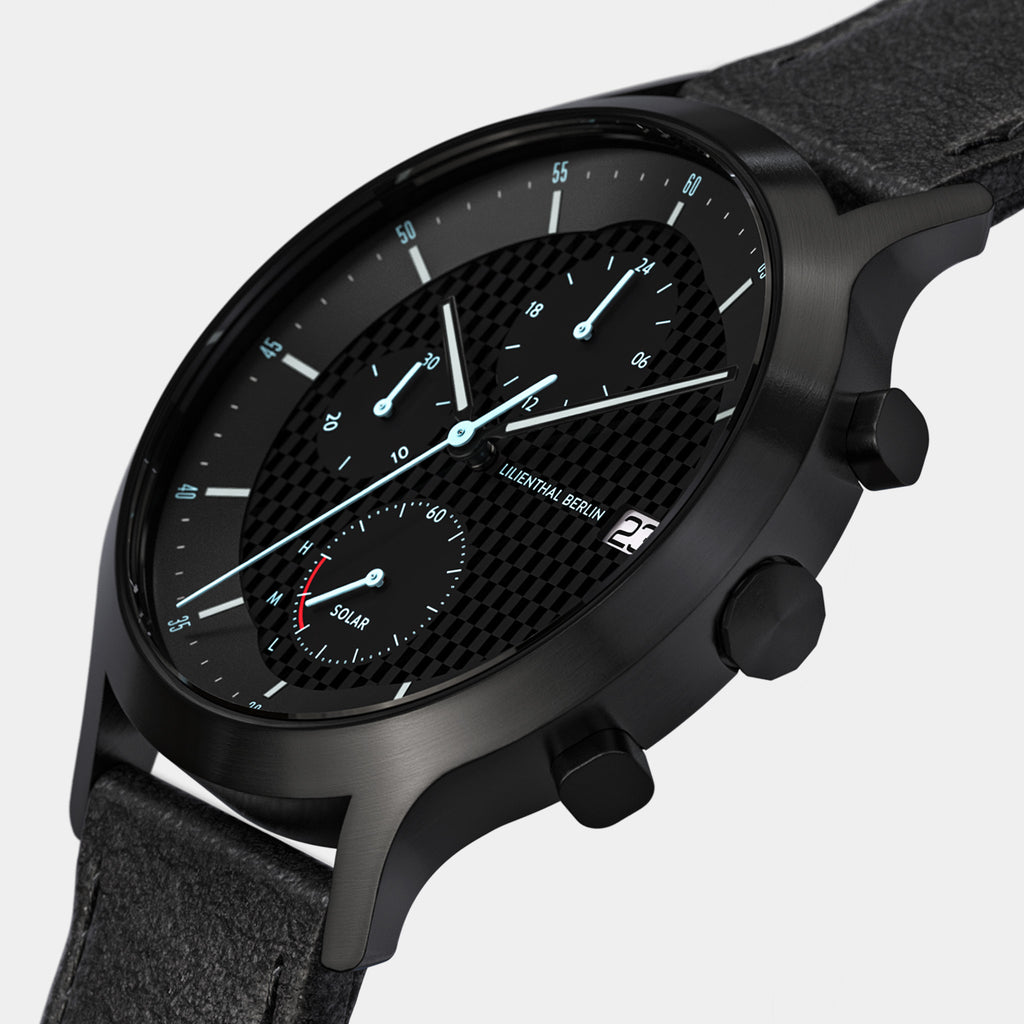 Black solar chronograph watch with textured dial, subdials, date window, and leather strap