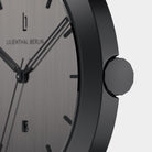 Close-up of minimalist black stainless steel watch with black dial and date window