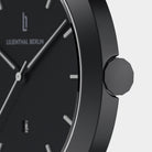 Close-up of minimalist black wristwatch with silver hour markers and geometric crown
