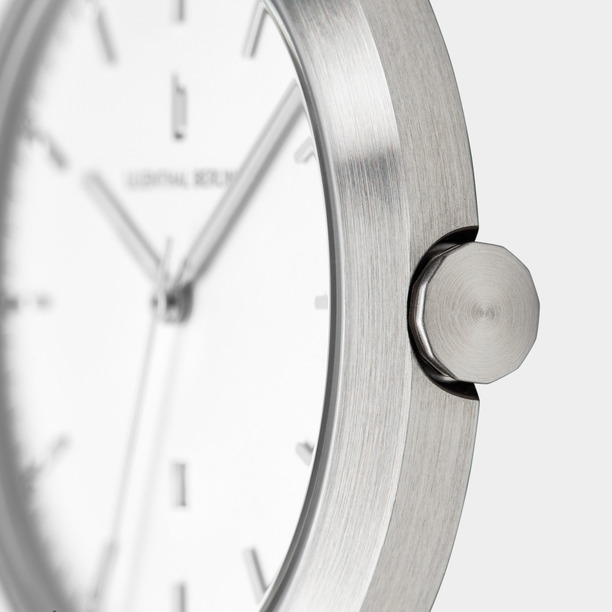 Close-up of minimalist silver watch with brushed stainless steel case and white dial