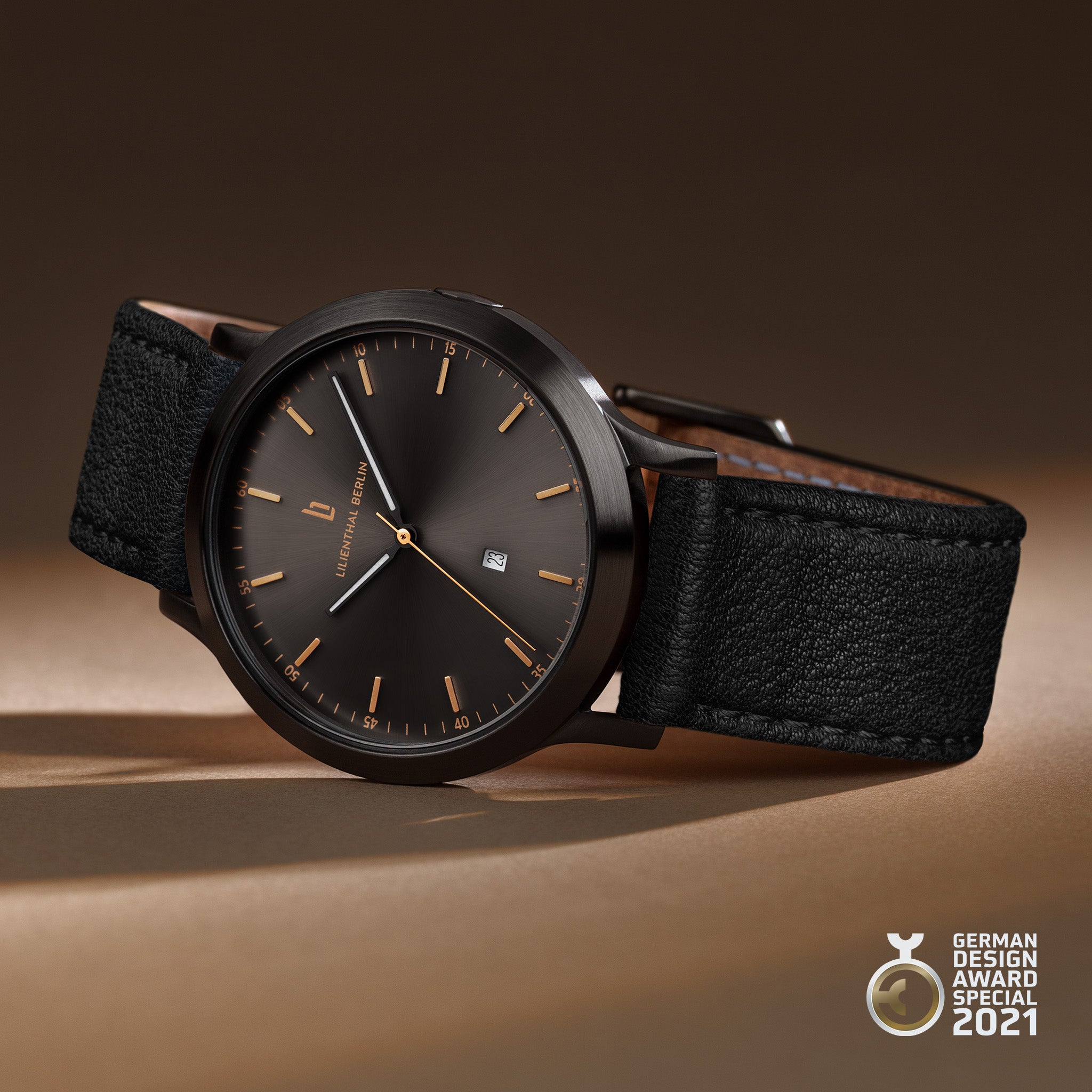 Minimalist black wristwatch with gold markers, black leather strap, date display, award badge