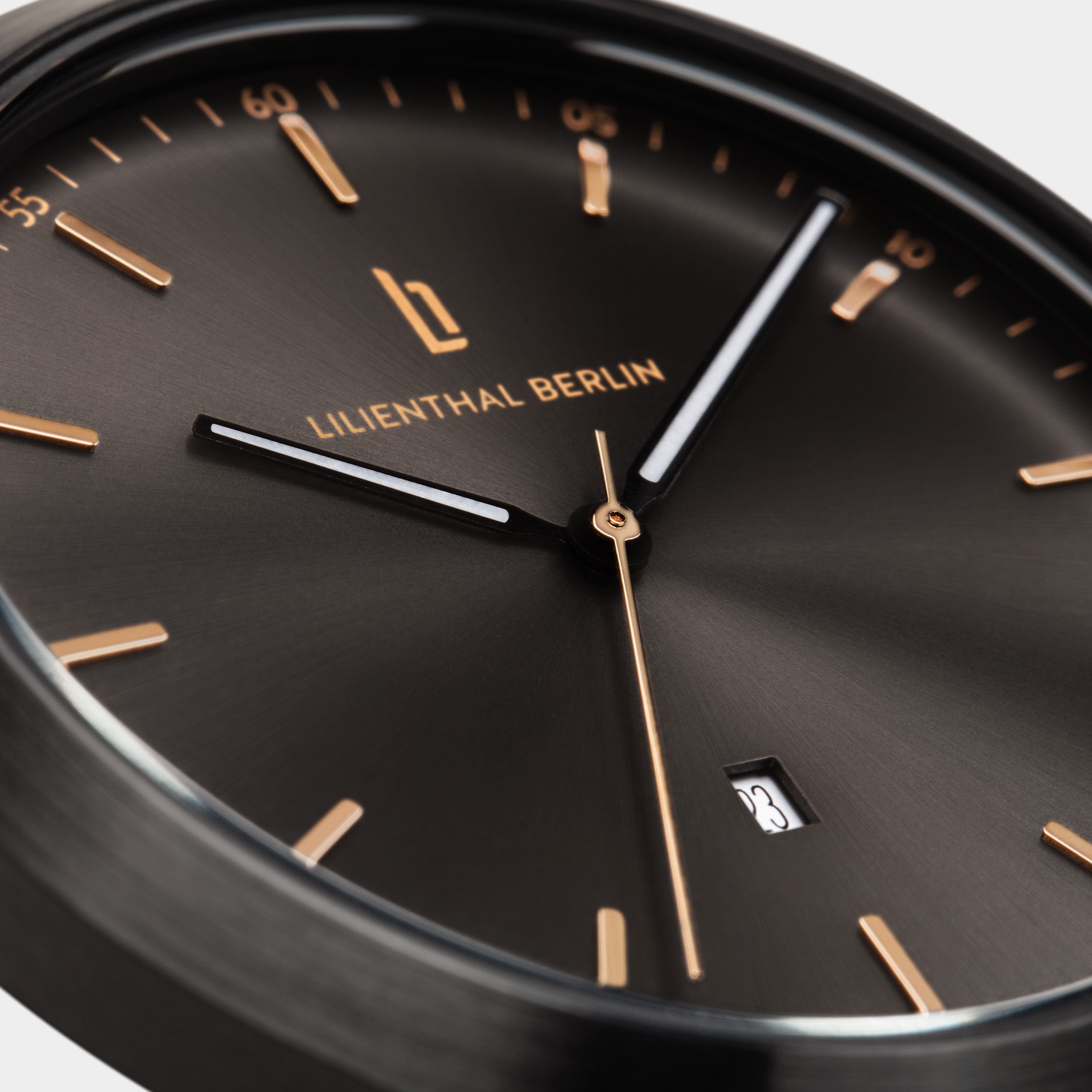 Close-up of a black minimalist watch with gold markers, date display, and sleek hands.