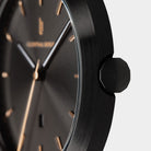Close-up of minimalist black wristwatch with gold hour markers and brushed metal case