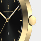 Gold watch with black dial, minimal hour markers, and date window, close-up view