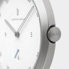 Minimalist silver wristwatch with white dial and silver hands, close-up side view