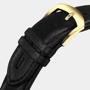 Black leather watch strap with gold buckle on light background